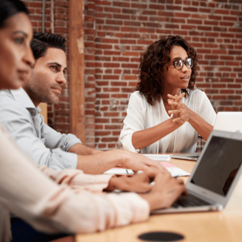 Group of employees gaining career clarity through Career Navigator coaching, smiling while working together on a laptop.
